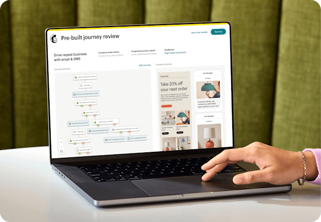 Image of a person sitting at a desk, looking at a laptop screen displaying Mailchimp’s Pre-built journey review feature. The feature shows a preview of an automation journey and an abstract view of email and SMS interfaces from the fictitious brand Assembly. 